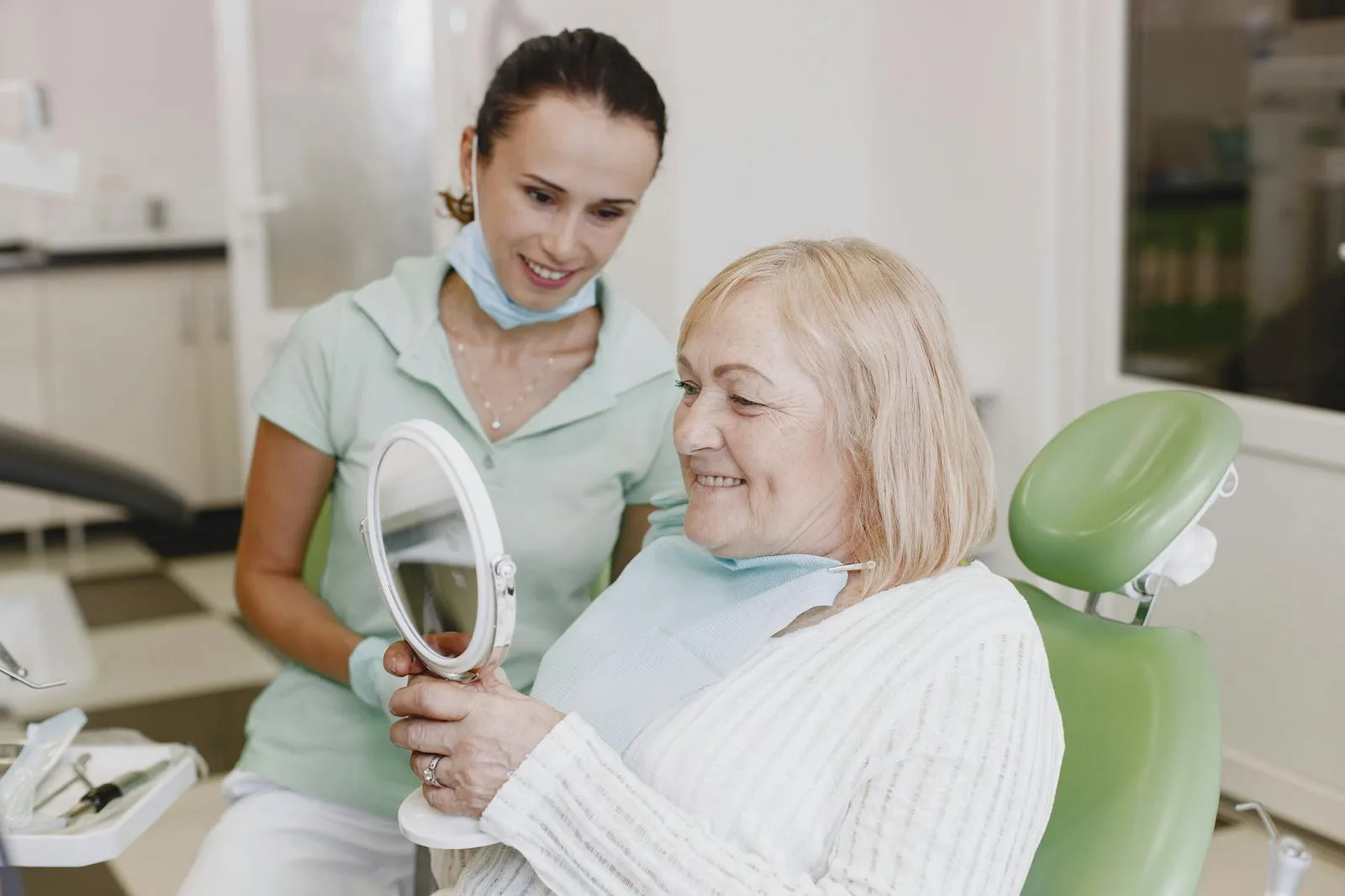 Paciente sorrindo com espelho durante avaliação odontológica